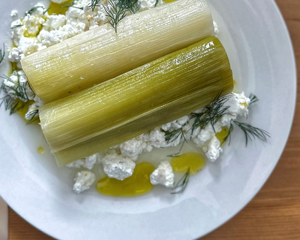 Two pieces of braised leeks plated on fresh curd cheese.