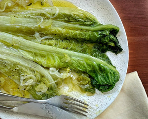 Romaine lettuce leaves on a speckled white plate drizzled with olive oil
